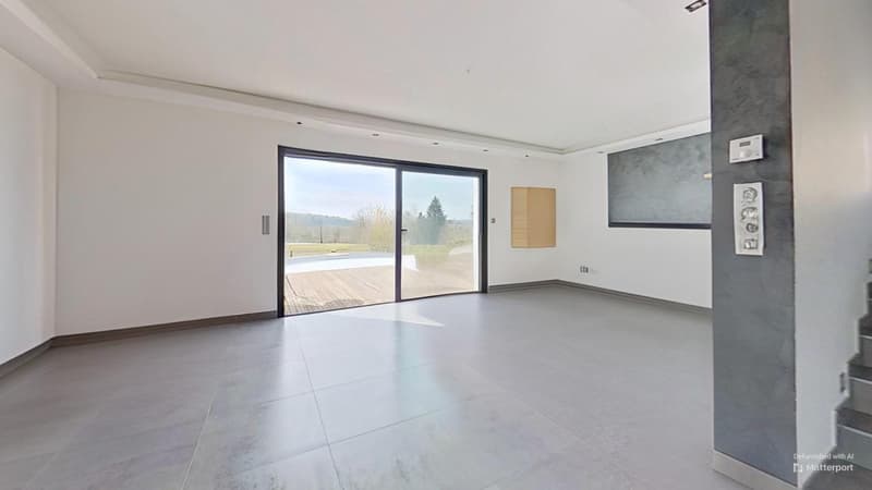 Spacious open-plan living room with large sliding glass doors leading to a balcony or terrace, hardwood flooring, and modern decor with minimalist wall art.