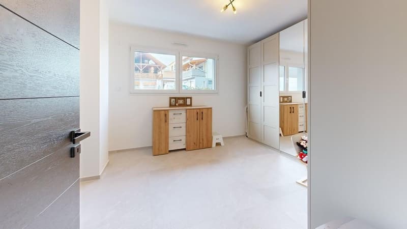 Empty room with white walls, white floor, wooden cabinet, window, and a mirror.