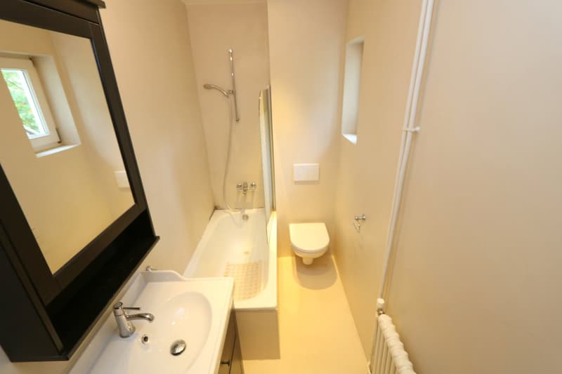Bathroom with bathtub, sink, toilet, mirror, white walls and floor, heating