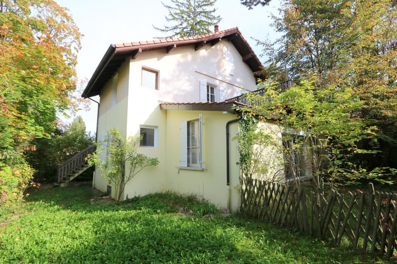 Two story house, yellow paint, white trim, brown tiled roof, stairs, balcony, wooden fence