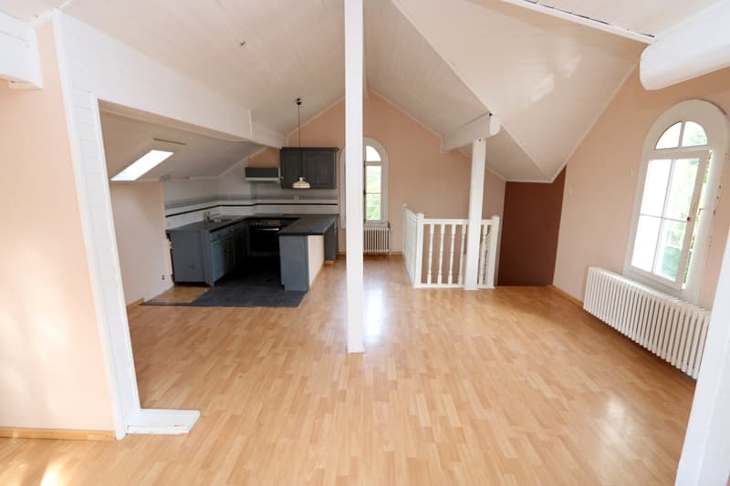 open attic space, kitchen area with appliances and sink, wooden floors, white walls, arch window