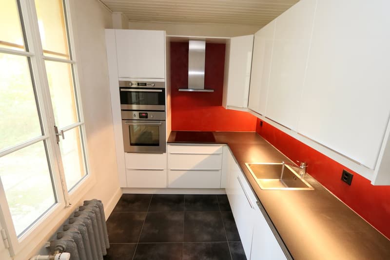 modern kitchen, white cabinetry, stainless steel appliances, large window, black tiled floor, gas stove, double oven, sink, faucet