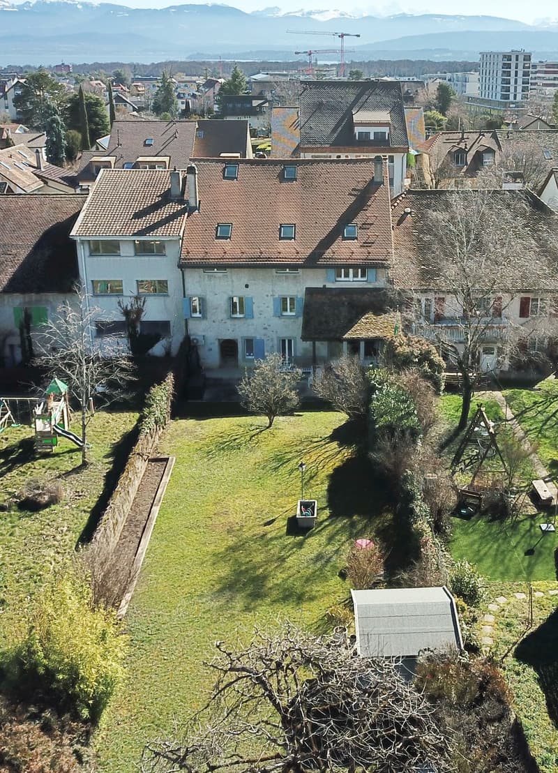 Building: multi-story, red roof, windows, garden, crane in the distance