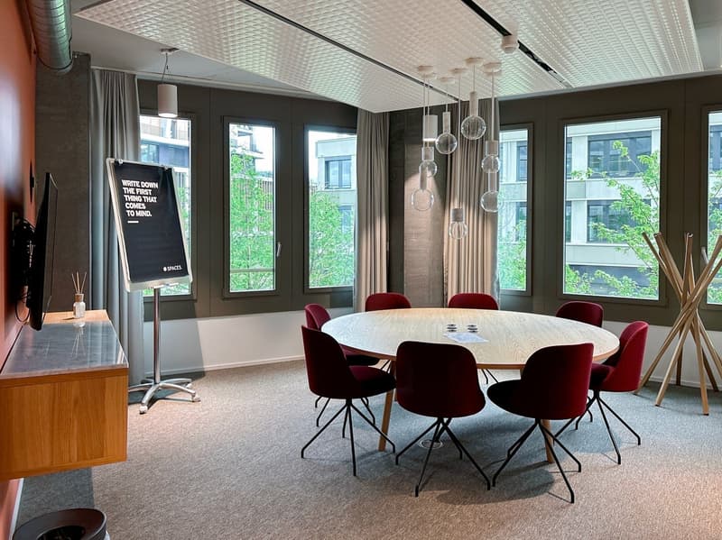 meeting room with a round table and chairs, large windows, and decorative hanging lamps