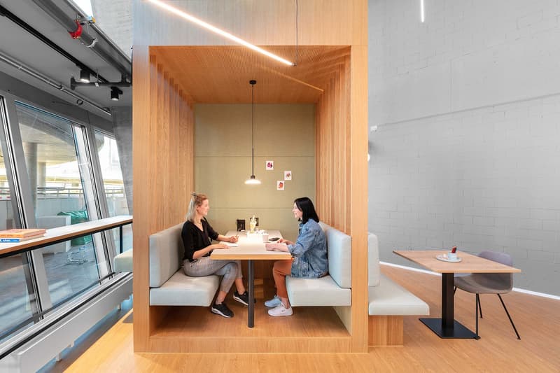 Wooden booth with built-in seating and table, modern design, large windows, simple decor, pendant lights