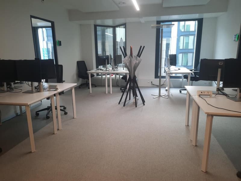 empty office space with tables, chairs, monitors, large windows, lamps
