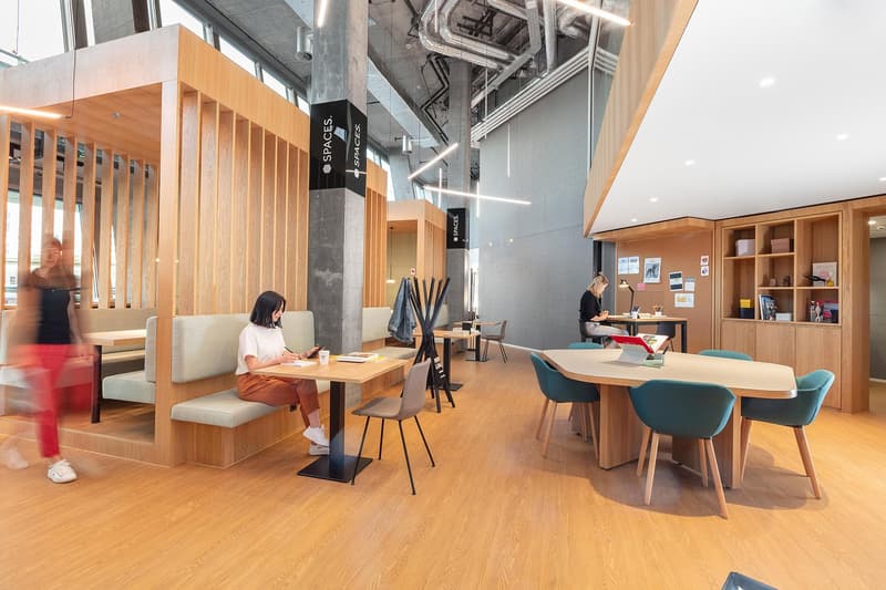 Open concept office space with wooden accents, comfortable seating areas, and a mix of individual and collaborative workspaces. The space features a dishwasher, indicating amenities for employees.