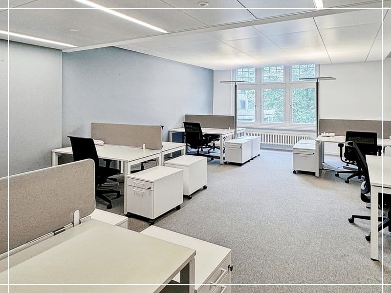 modern office space with white desks, black chairs, gray walls, white ceiling, large windows, white cabinets, and white flooring