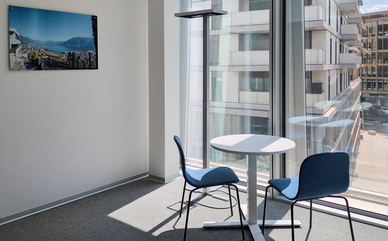 minimalist room with white desk, blue chairs, gray carpet, picture on wall, and glass window with city view