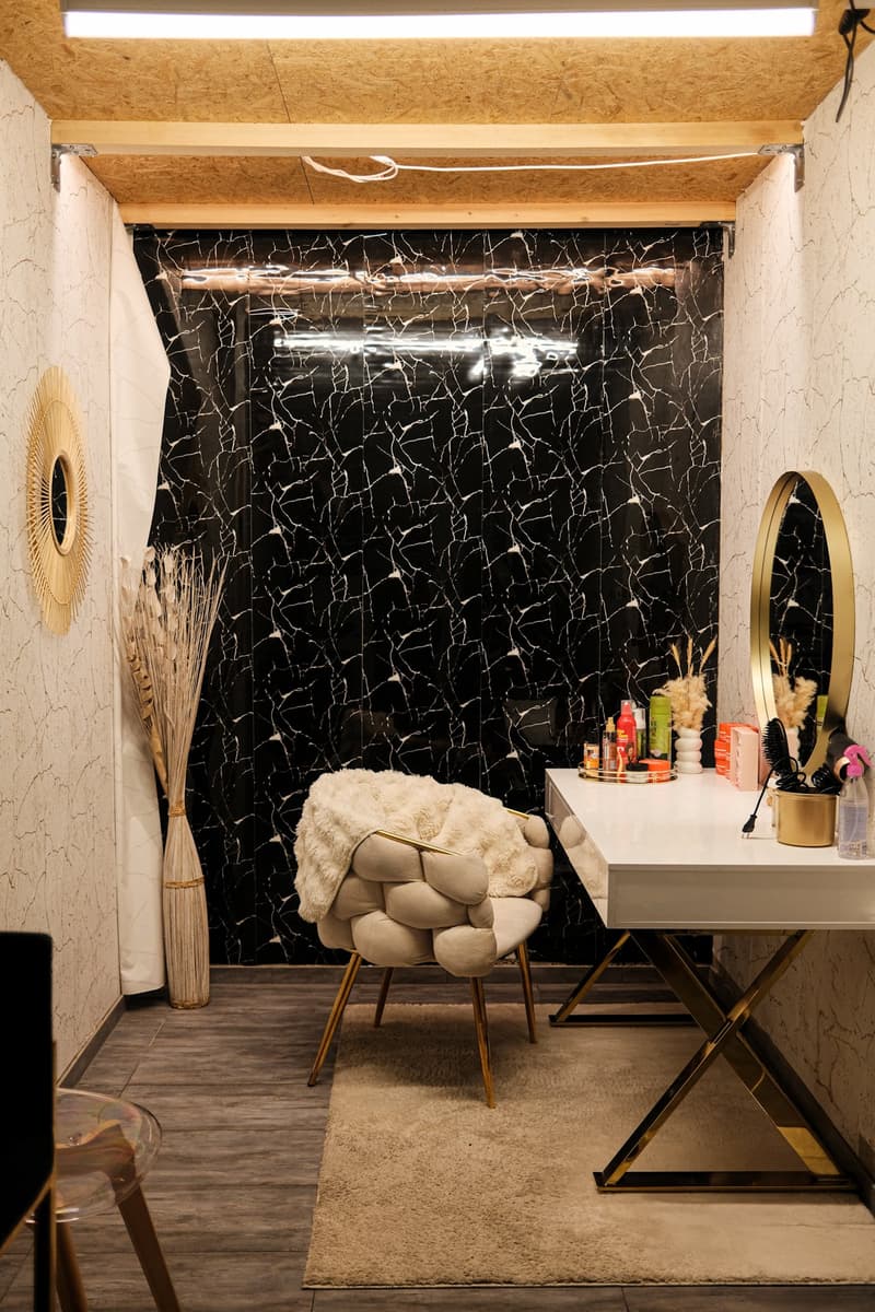Bathroom with black and white marble-patterned walls, a furry chair, a vanity with cosmetic items, and a mirror on the wall.