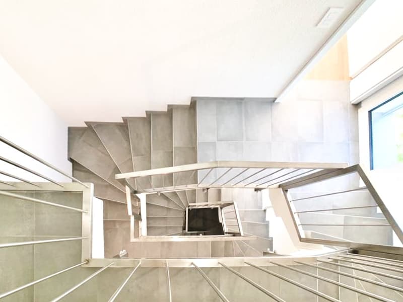 Concrete spiral staircase with multiple levels, leading up to a higher floor or level