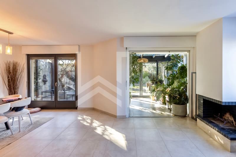 Corsier / the entrance to a modern house with a fireplace, a bench, and large doors
