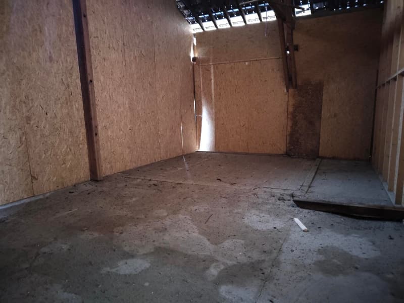 Concrete floor, wooden pillars, exposed beams, unfinished walls, small gap at one wall