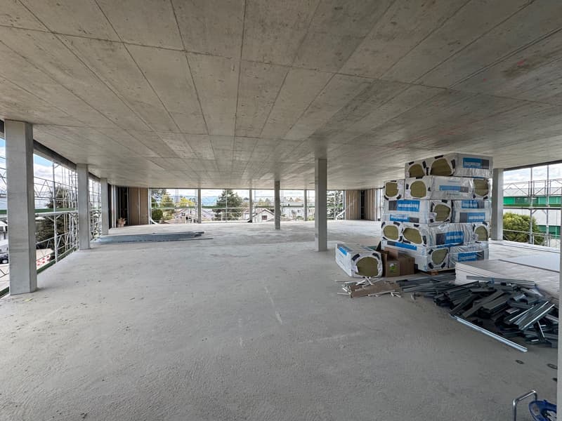 unfinished room, concrete floor, large windows, construction materials
