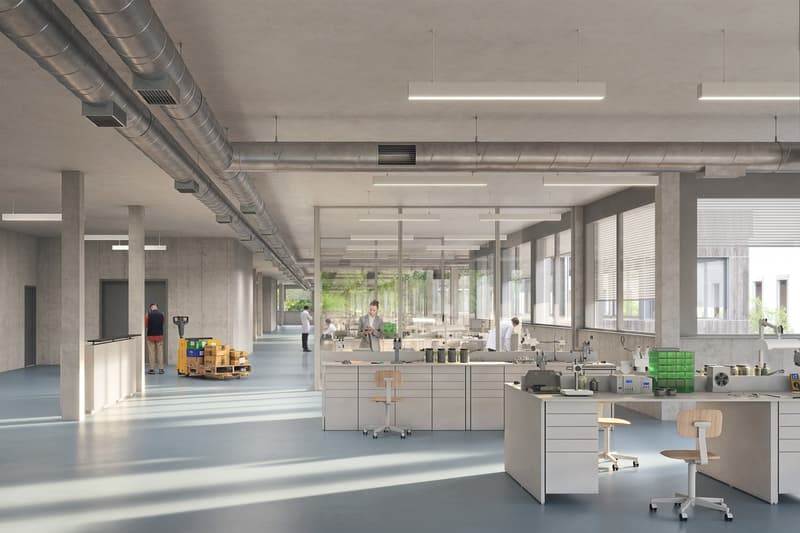 interior of a building with many windows, glass walls, tables, people working, and some industrial equipment