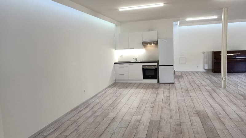 Open kitchen with wooden floors, white cabinets, integrated refrigerator, oven, sink with faucet, modern lighting, and an open area.