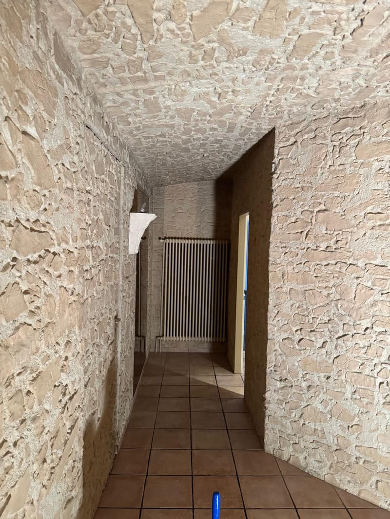stone wall, brown tile floor, hallway with radiator