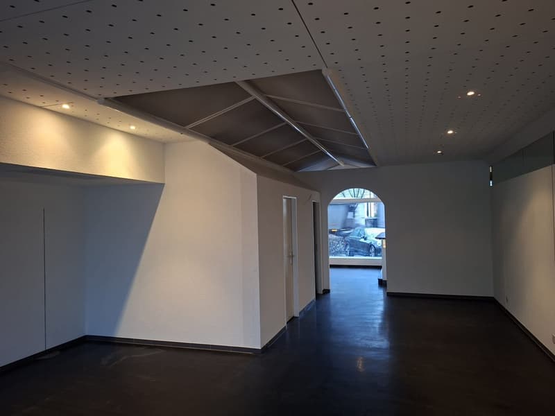 wide open space, plain walls, black floor, an arch doorway, cars outside the window
