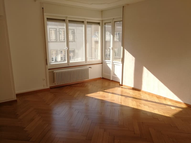 empty room, wooden floor, radiator, large windows, bright sunlight