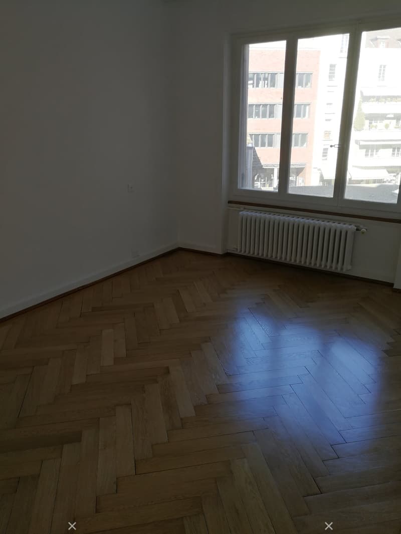 empty room, wooden herringbone flooring, white walls, window, radiator