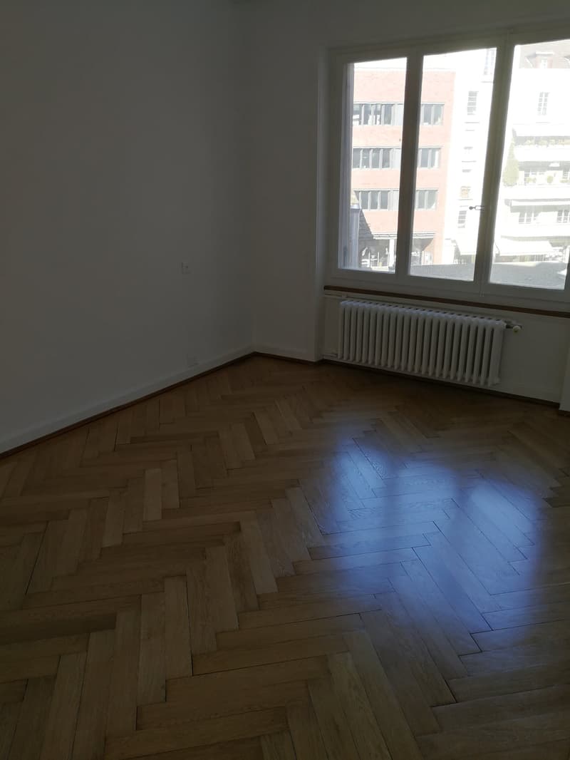 empty room, wooden herringbone flooring, white walls, window, radiator