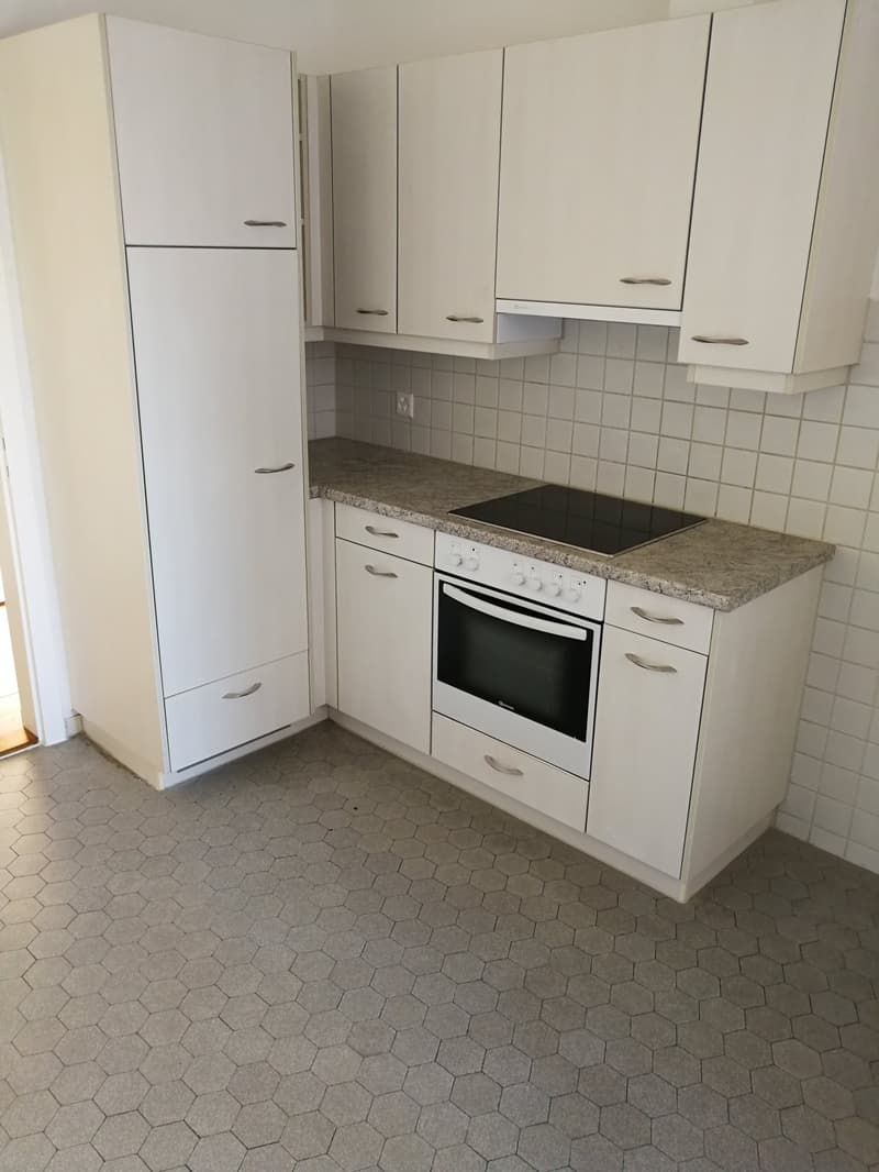 modern kitchen, white cabinets, tile flooring, granite countertop, white built-in oven, black induction cooktop, integrated sink and faucet, refrigerator
