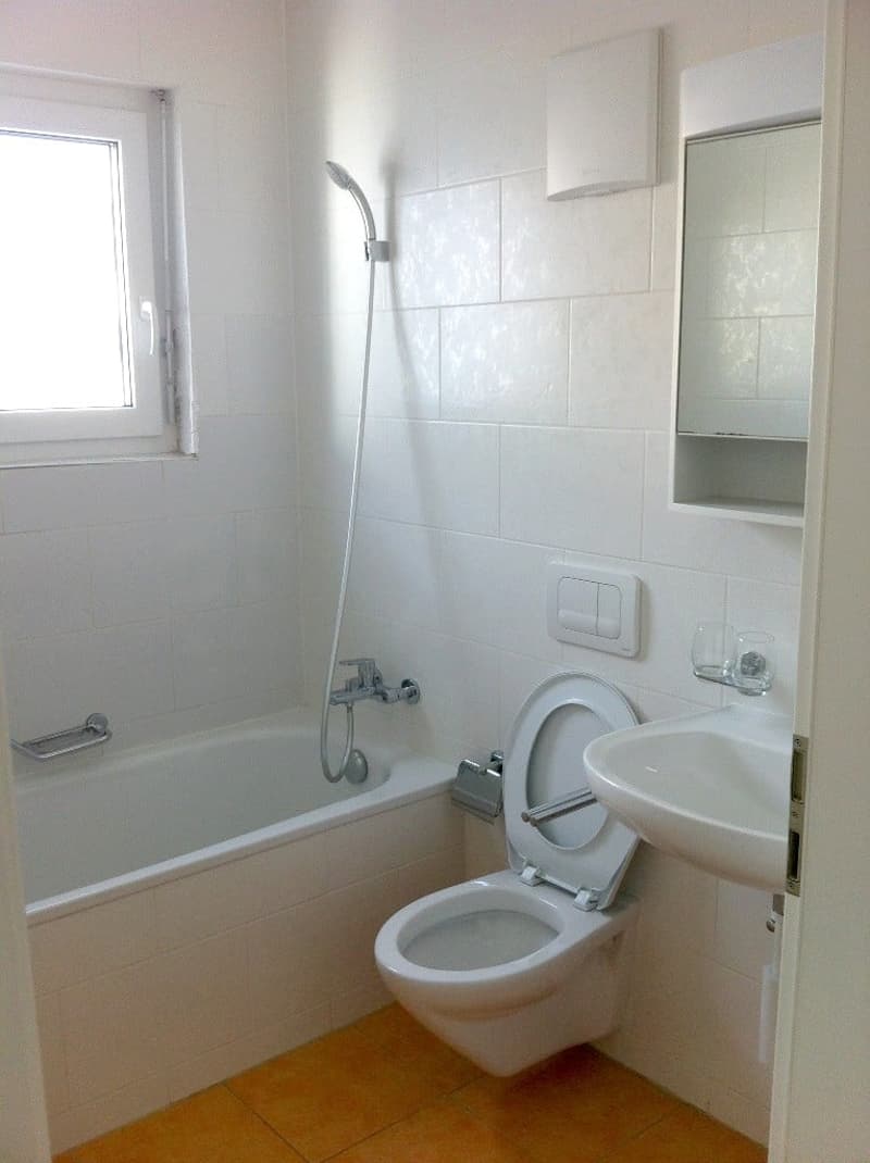 White tiles, white bathtub, shower head, toilet, sink, mirror, glass holder