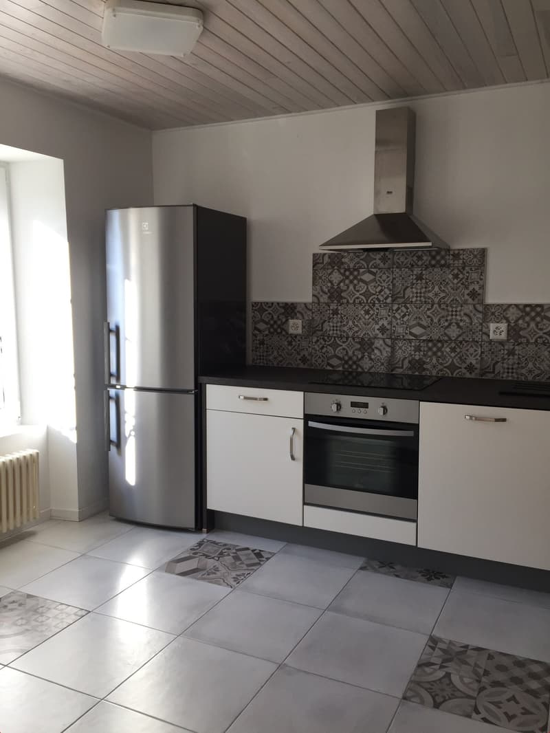 A modern kitchen with white cabinets, stainless steel appliances, tiled floor, and an open layout.
