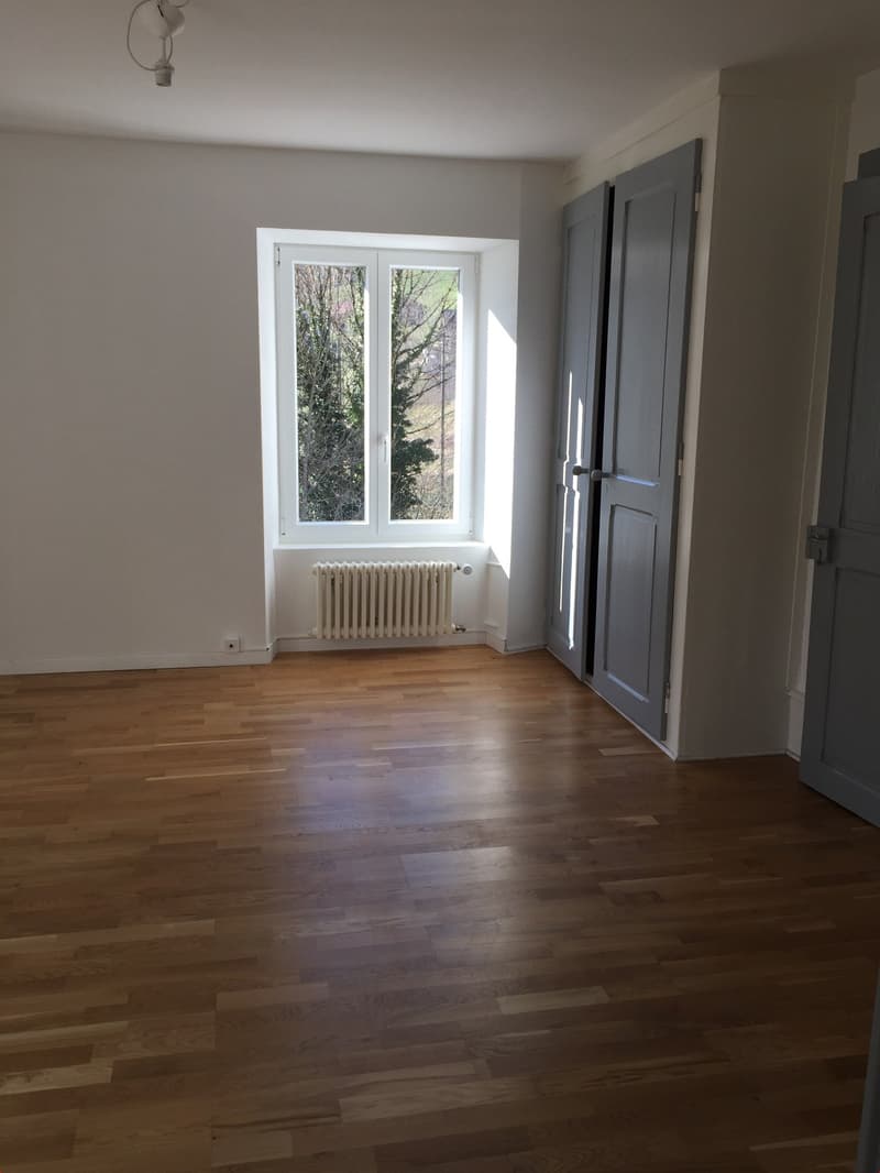 empty room, wooden floor, white walls, radiator under window, window with view outside