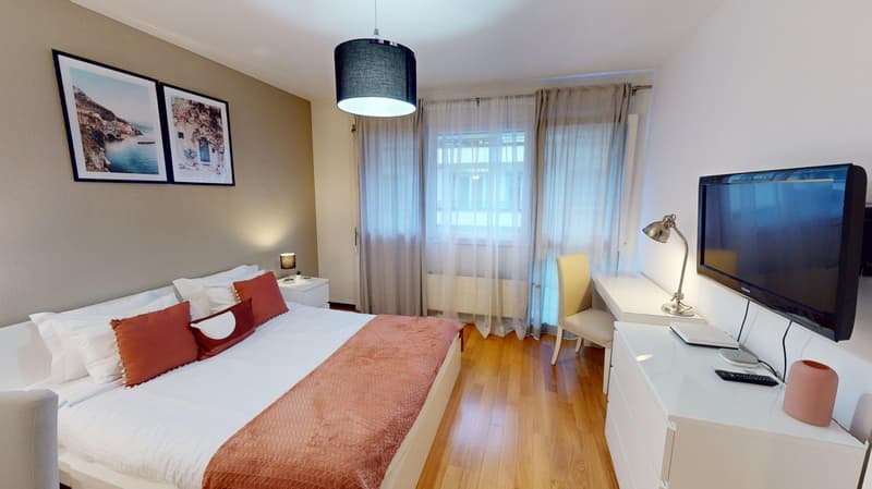 Double bed, white walls, white furniture, television, desk, lamps, paintings