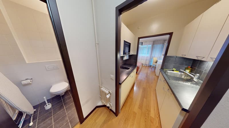 modern kitchen with sink, stove, kitchen cabinets, bathroom with toilet, radiator, white tiled wall, washing machine