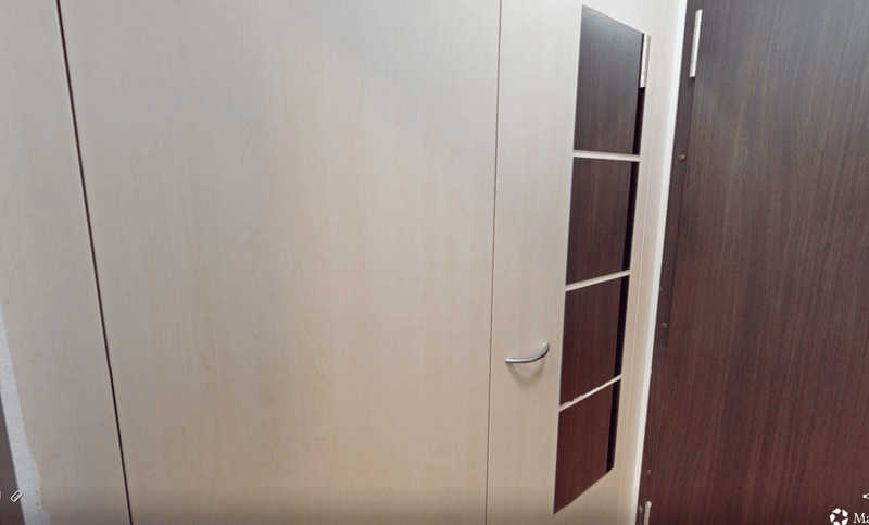 Closed white and brown wooden door, with silver handles, shelves on the door