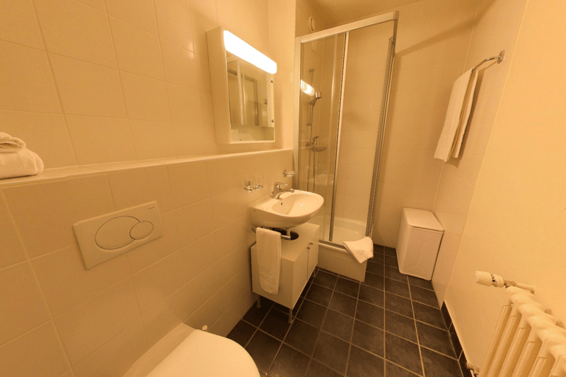 Tiled bathroom with a sink, mirror, shower stall, and a washing machine.