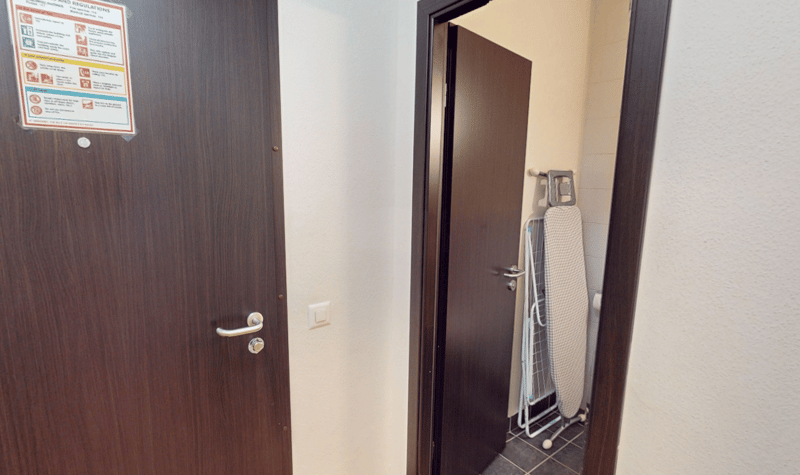 interior of a small room, door, and an ironing board