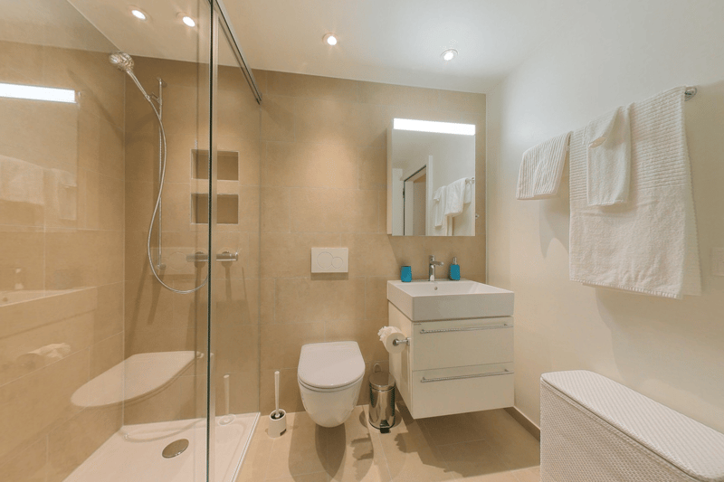 Modern bathroom with shower, sink, toilet, tiled floor, mirror, and towel racks