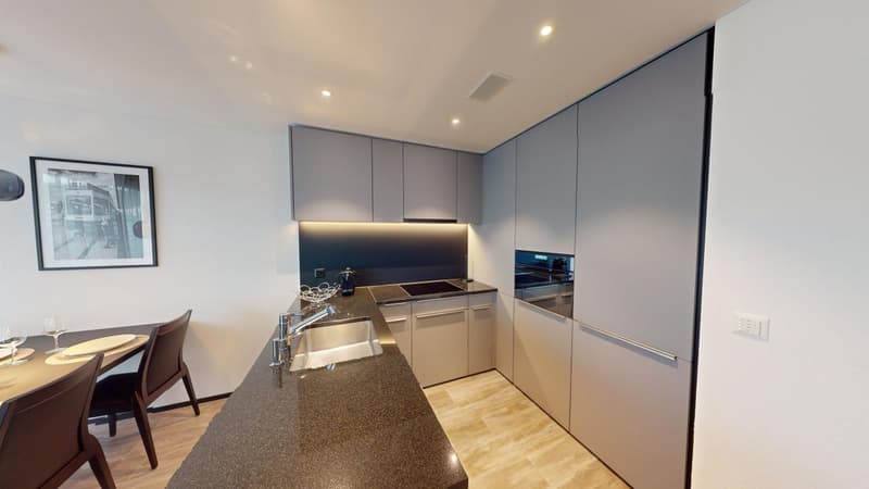 Modern kitchen with gray cabinets, stainless steel appliances, granite countertops, and a dining table