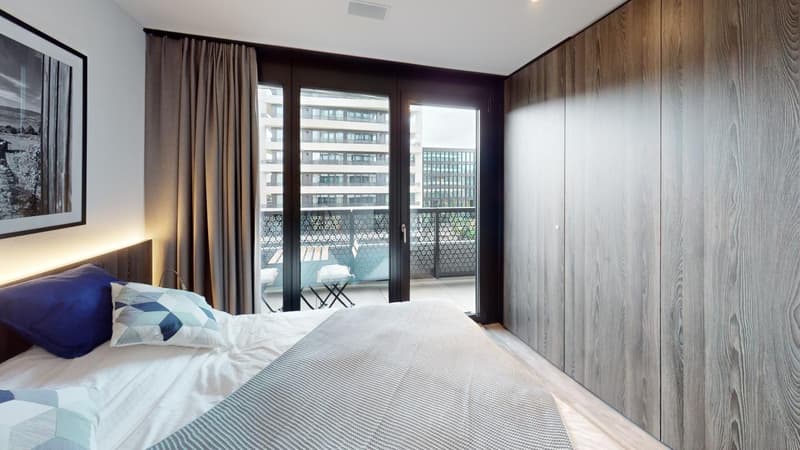 wooden walls, glass double doors to balcony, bed with pillows, side table