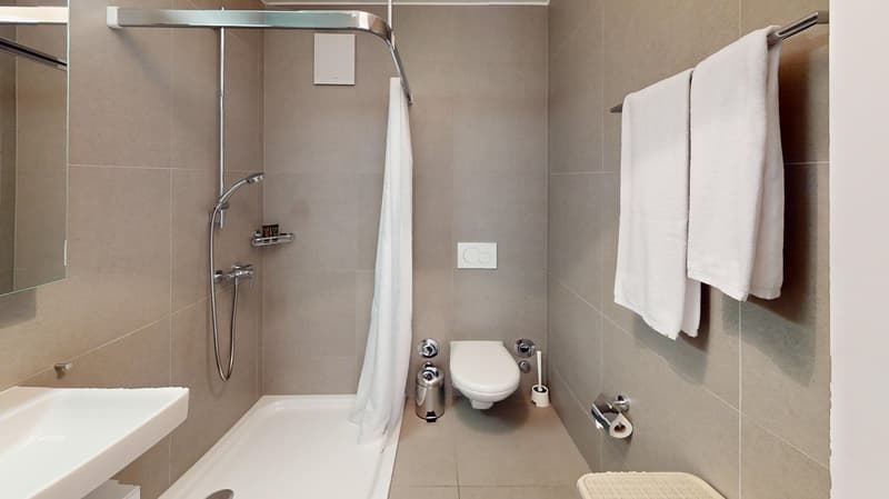 white tiled walls, silver faucet, shower enclosure, toilet, mirror, towels, foot stool