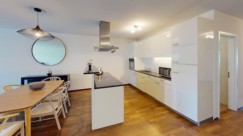 modern kitchen with wooden floor, white cabinets, black countertop, microwave, and white sink