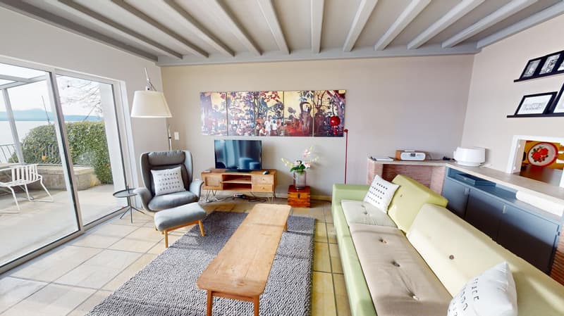 modern living room, large sliding windows, grey carpet, green couch, table, chair, TV, fireplace, glass balcony