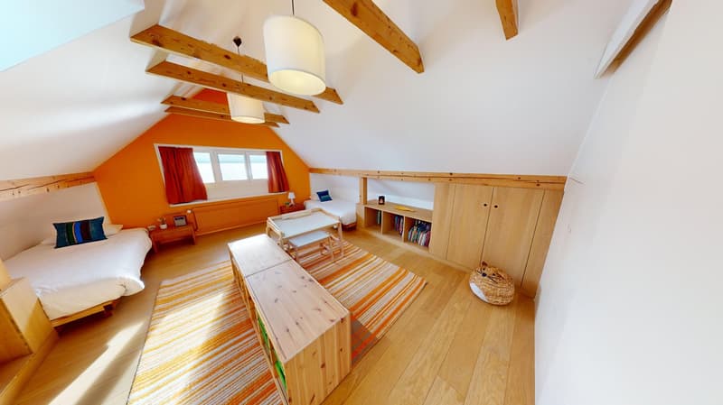orange painted wall, wooden beams, 2 beds, storage shelves, small table, desk lamp, striped rug, basket