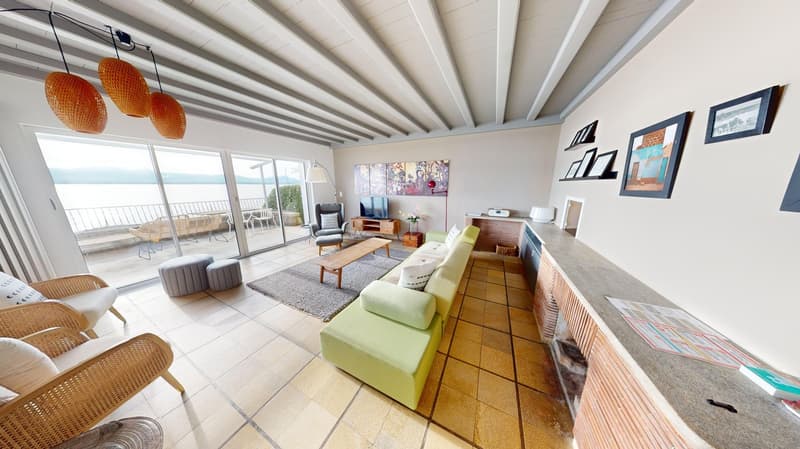 open living room with sliding doors leading to balcony, large windows, fireplace, wooden coffee table, sofa, armchairs, lamps, wooden cabinet, paintings on wall, floor lamp