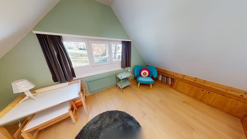 angled ceiling, wooden floor, desk with lamp, chair, bookshelf, radiator, small rug, large window with curtains