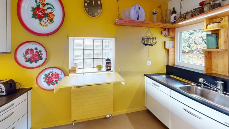 Yellow walls, white countertop, sink, toaster, drawers, shelves, decorative plates, wooden basket