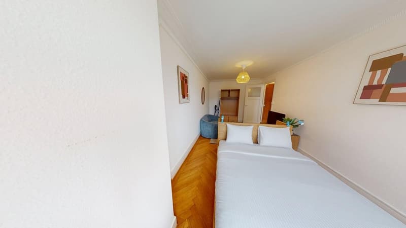 double bed, wooden floor, white walls, two pillows, white linens, light fixture, armchair, closet, frame