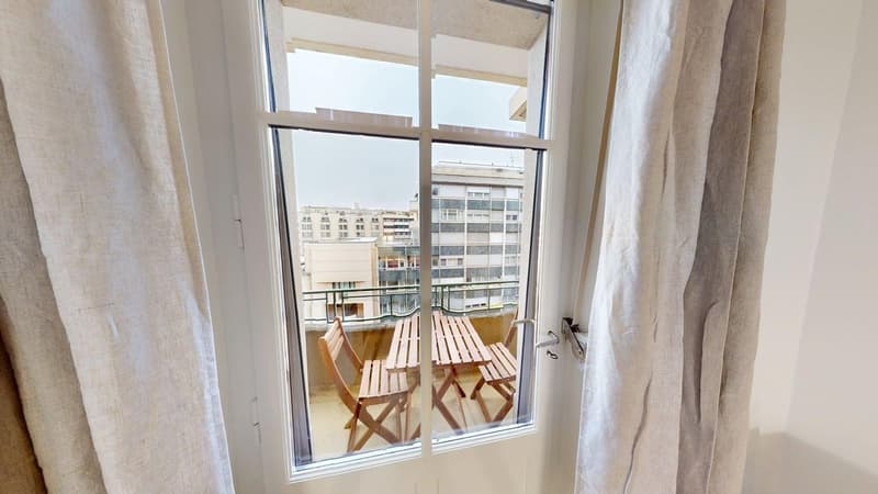 Wooden balcony with two chairs and a table, view of a city