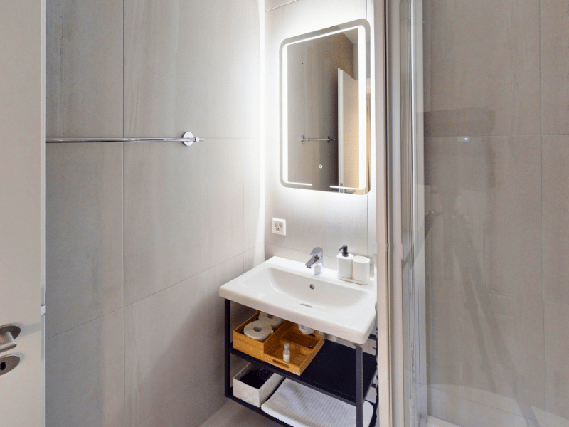 white tiles, sink, mirror, shower, storage, towels, soap