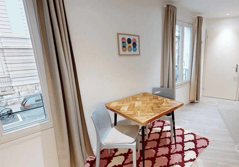 Dining table with two chairs, large window, rug, framed picture, doorway