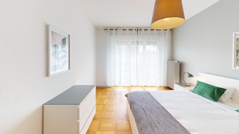 Bedroom with wooden floor, white walls, bed, nightstands, lamp, picture frame, curtains, radiator, and a cabinet.