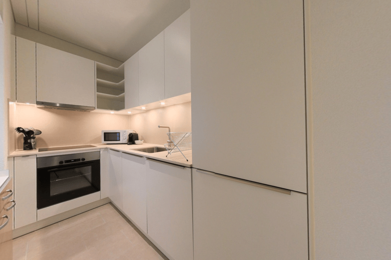 Modern, minimalist kitchen with white cabinets, built-in appliances including a dishwasher, and a clean, streamlined design.